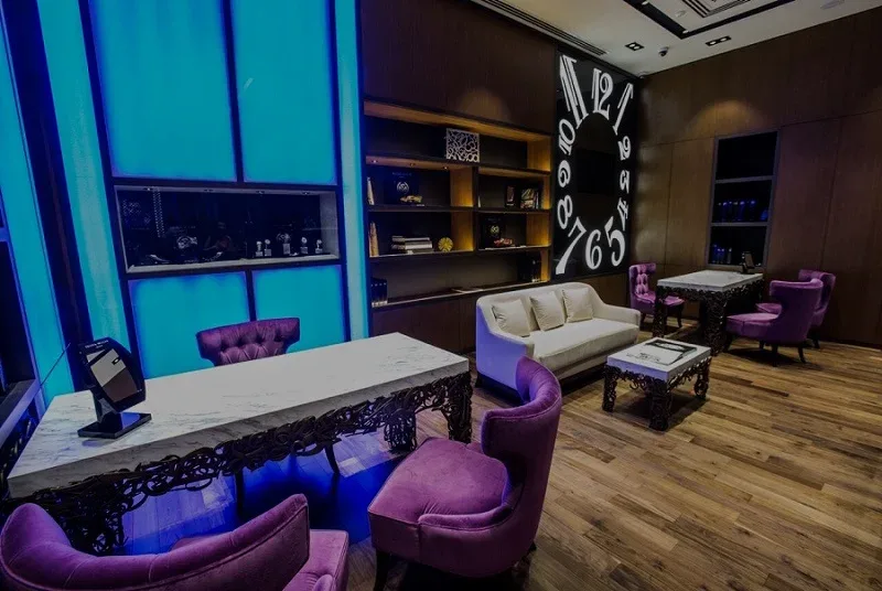 Lounge area of the Franck Muller Dubai boutique with marble table, purple velvet seating and wall of numerals