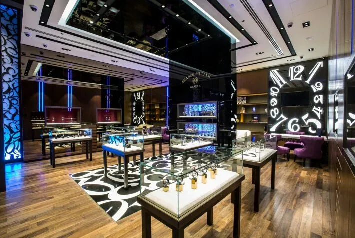 Main salon of the Franck Muller Dubai boutique with glass display cases and a wall of oversized numerals