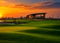Panoramic golden hour sunset over the championship fairways, putting green, and modern clubhouse at Trump International Golf Club Dubai